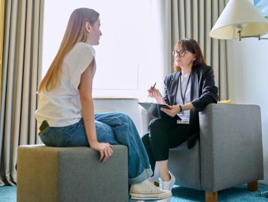 Therapeutin spricht mit Patientin im Beratungsgespräch und macht Notizen.